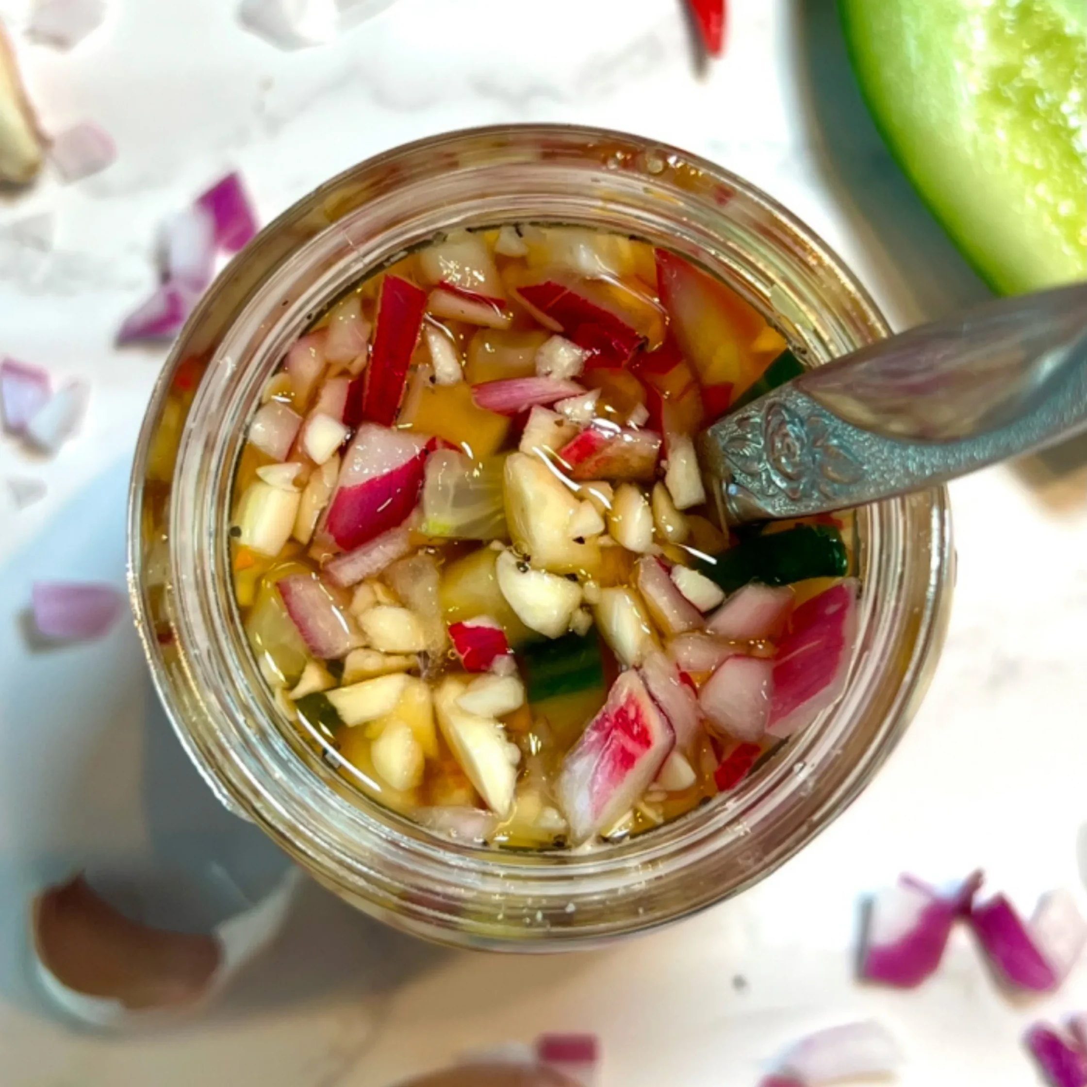 Chopped onions and red peppers in a brine-filled glass jar, ready for pickling/liquor.