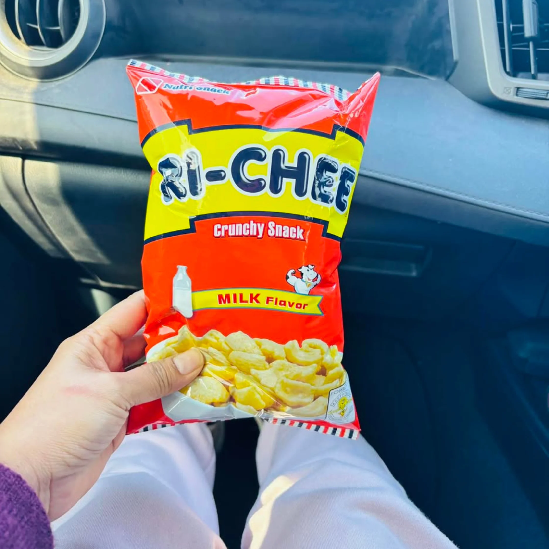 Person in a car holding an opened bag of Crunchy Snack potato chips with a milk flavor label visible at the bottom of the bag.Lumpia Shanghai PHOTO COURTESY OF The Fat Gourmand Official Facebook