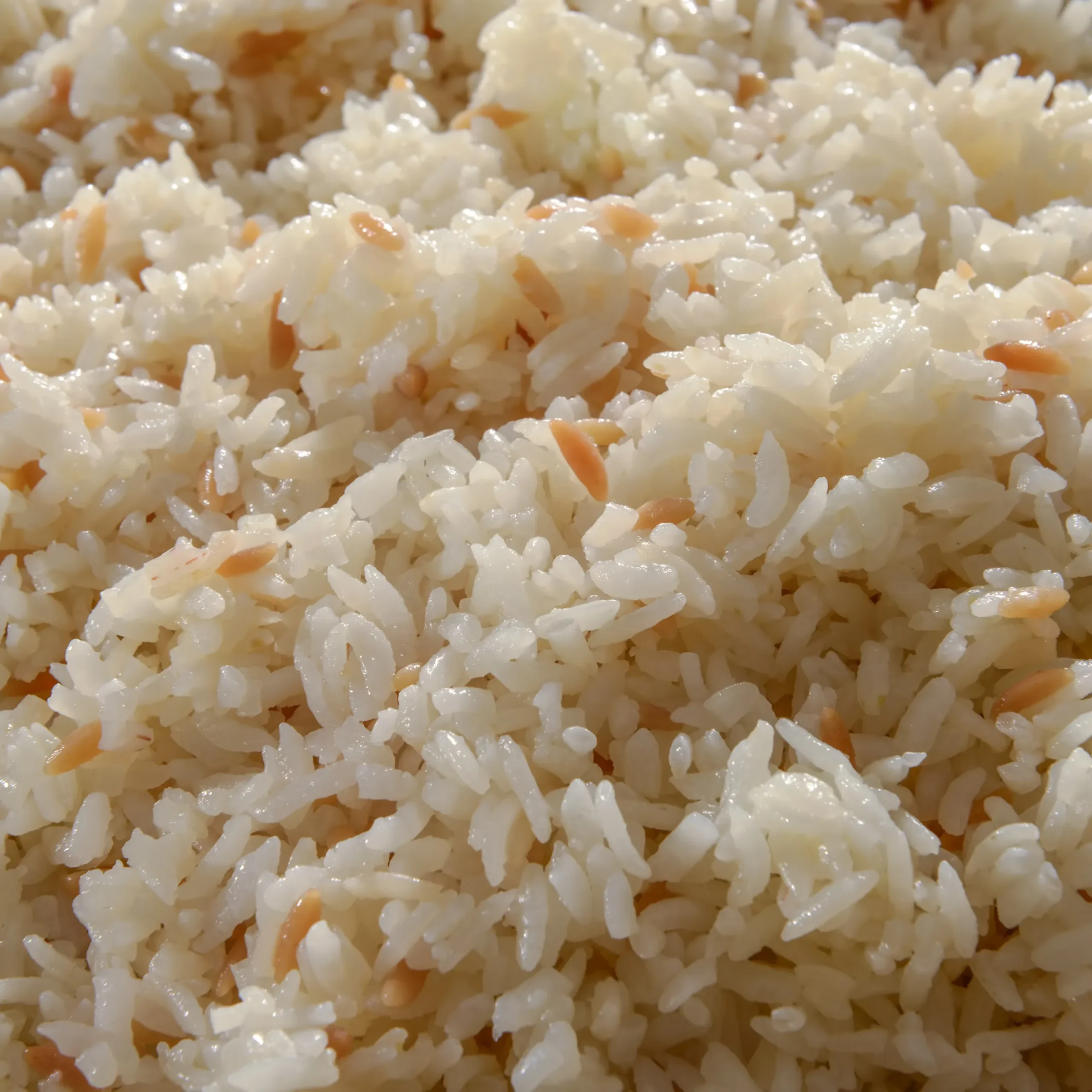 Close-up of fluffy cooked white rice with small orange bits mixed in.