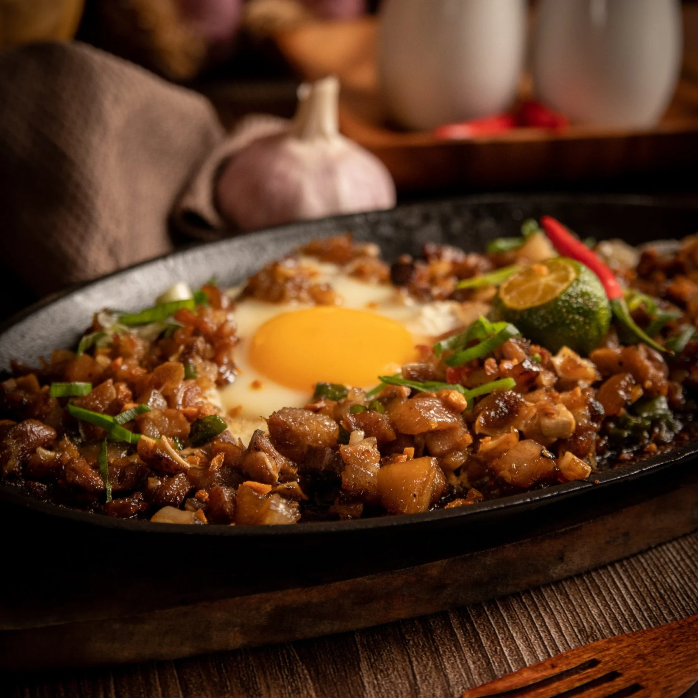 Skillet dish with browned ground meat, chopped vegetables, and two sunny-side-up eggs visible on top.