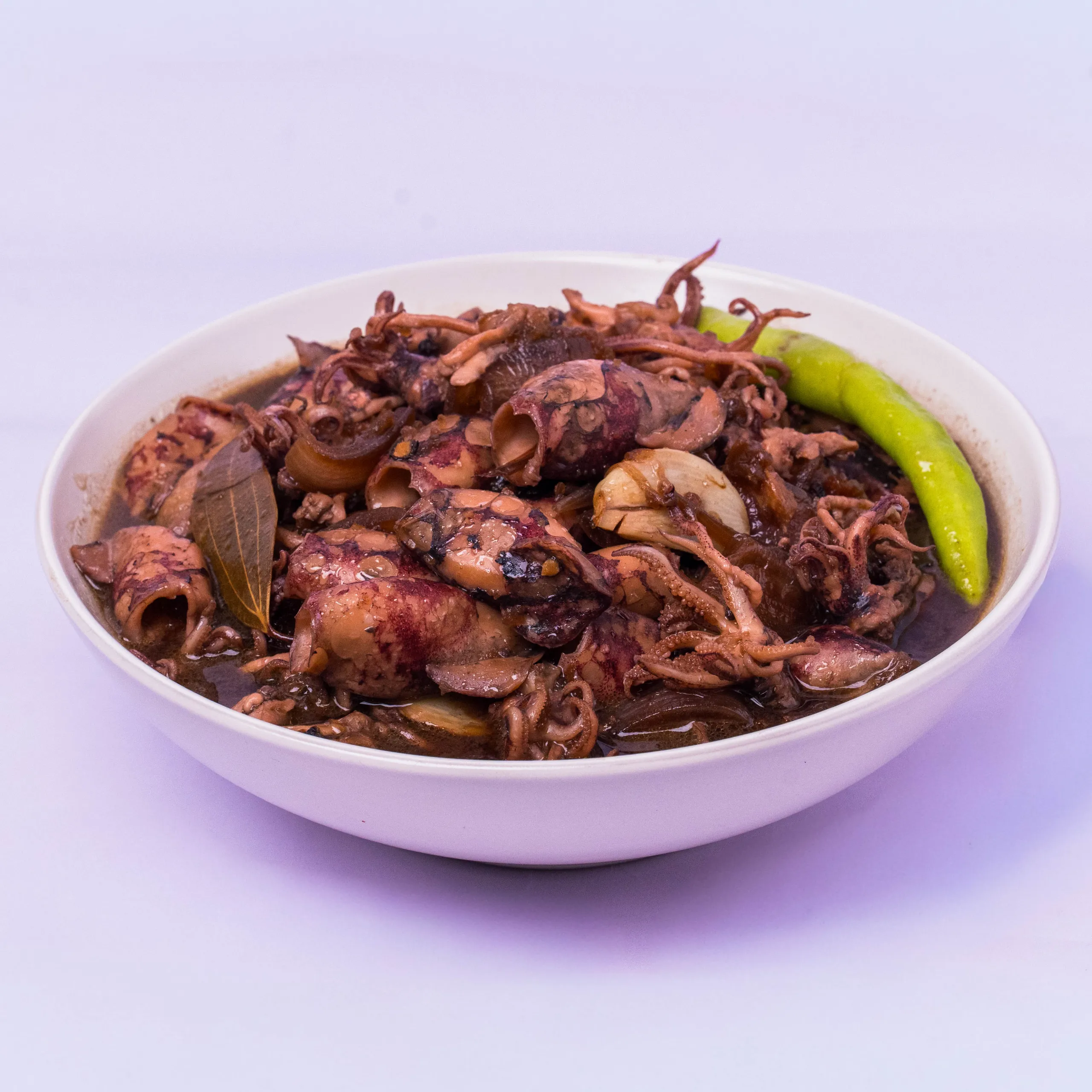 White bowl filled with shredded meat, onions, and a bright green chili pepper on a light purple surface.