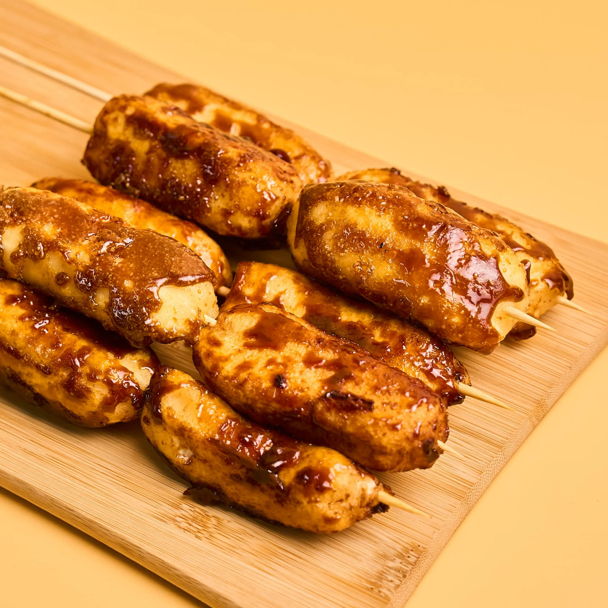 Grilled chicken skewers with glossy glaze on a wooden board