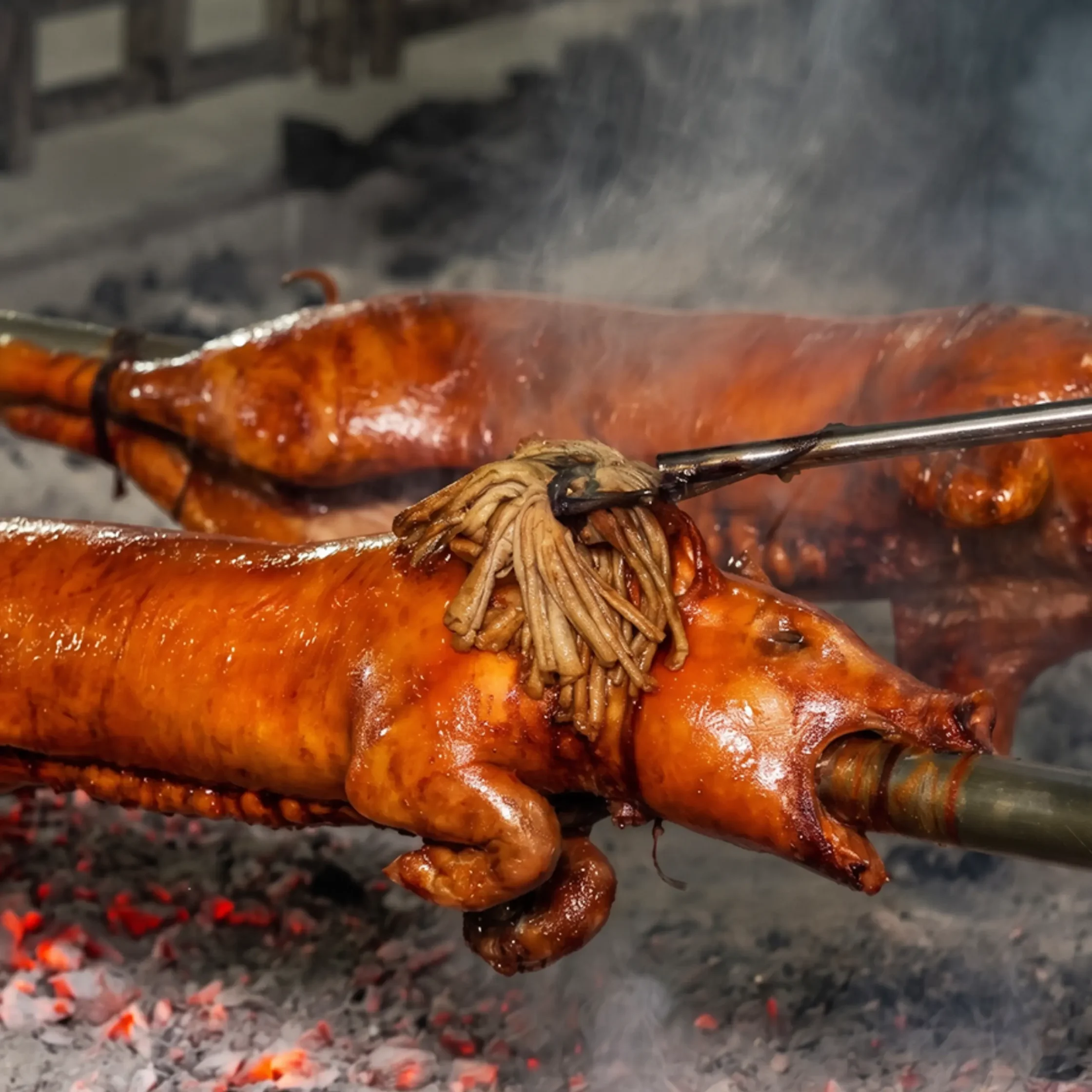 basting two roast pigs over charcoal fire