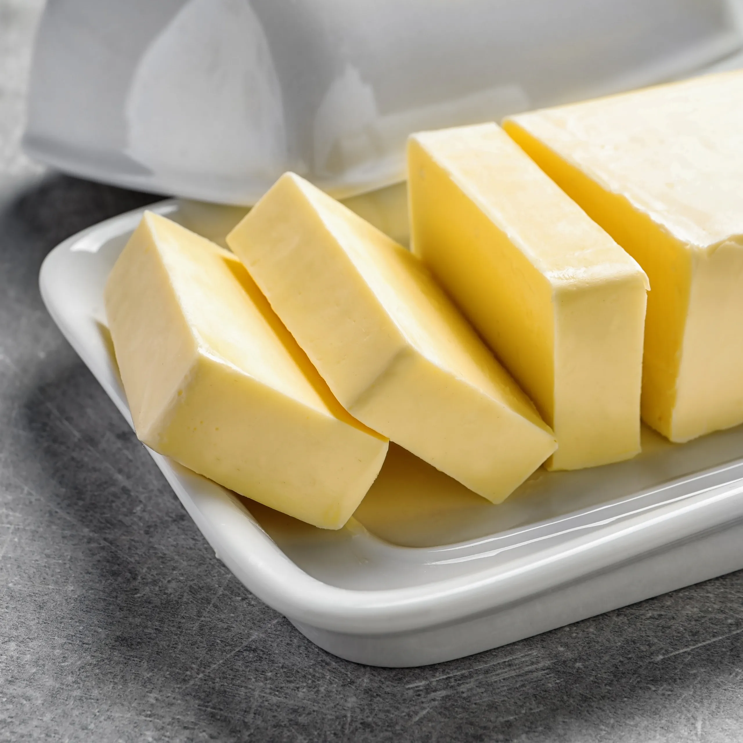Butter cubes arranged on a white dish, ready for use in cooking or baking.