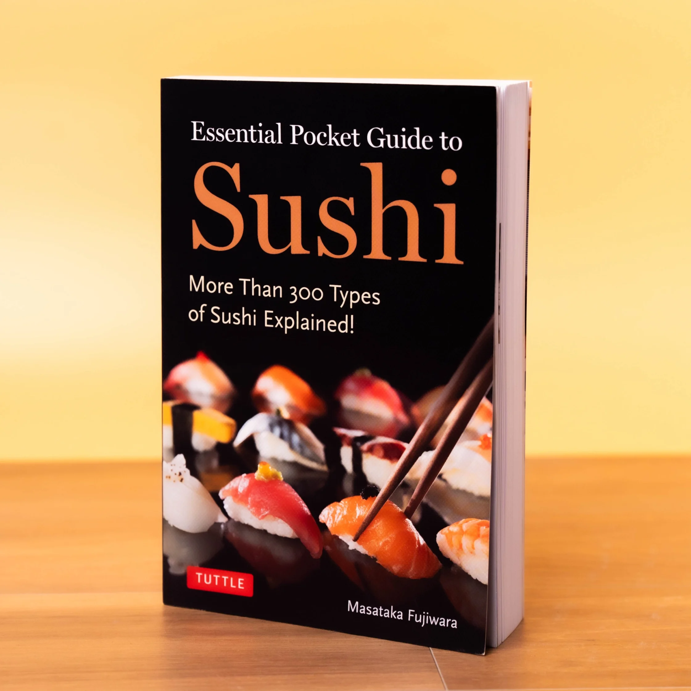 Front cover of a sushi cookbook on a yellow background; title reads Essential Pocket Guide to Sushi. verst.