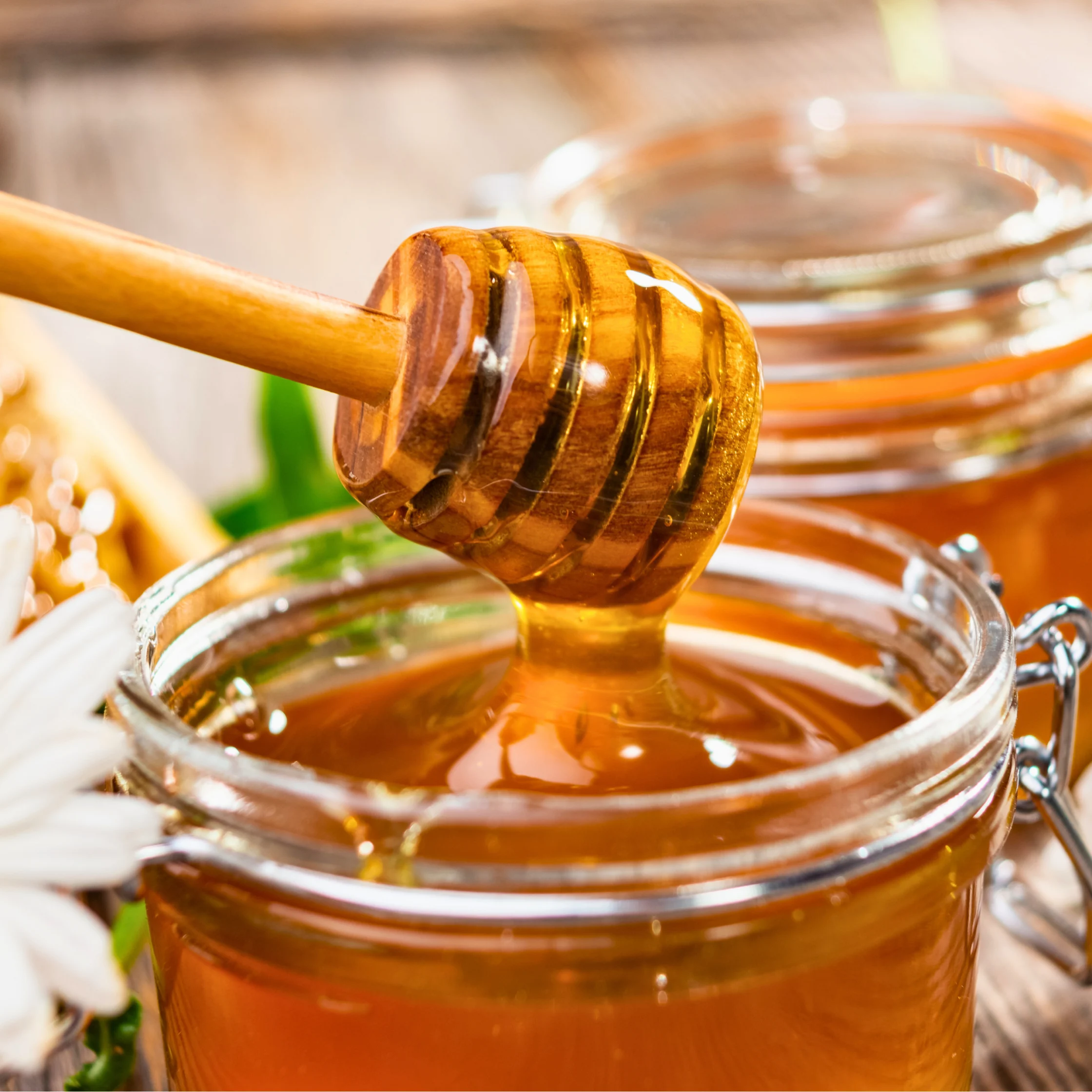 golden honey in jar with flowers around it