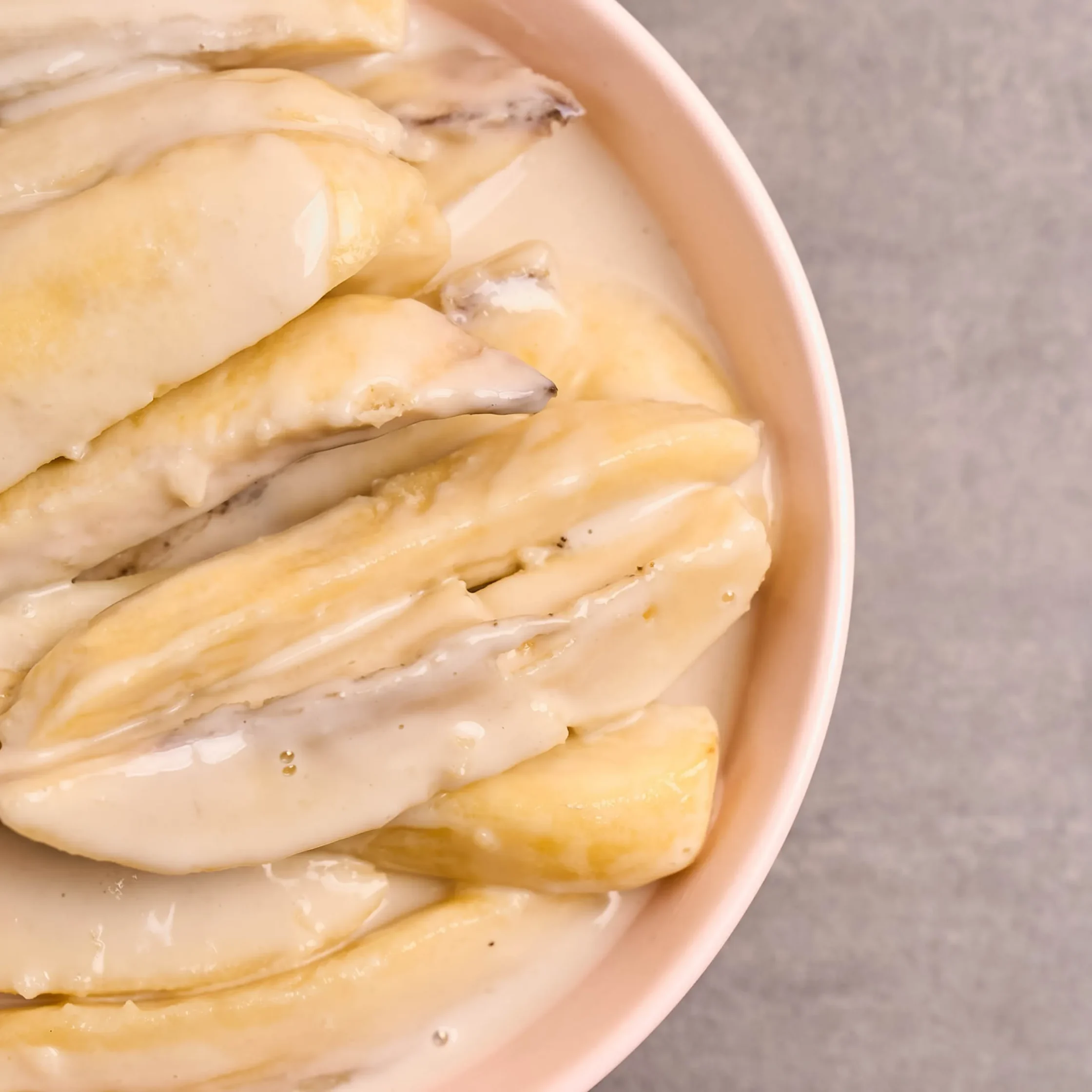 Close-up of pale rolled dough pieces glazed with oil in a light pink bowl