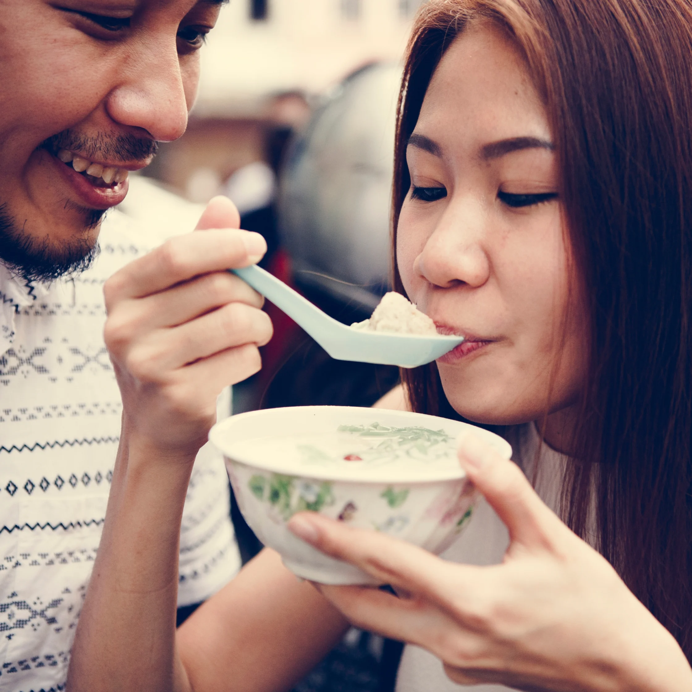 a woman slurping a warm bowl of savory ramen with borth and noodles