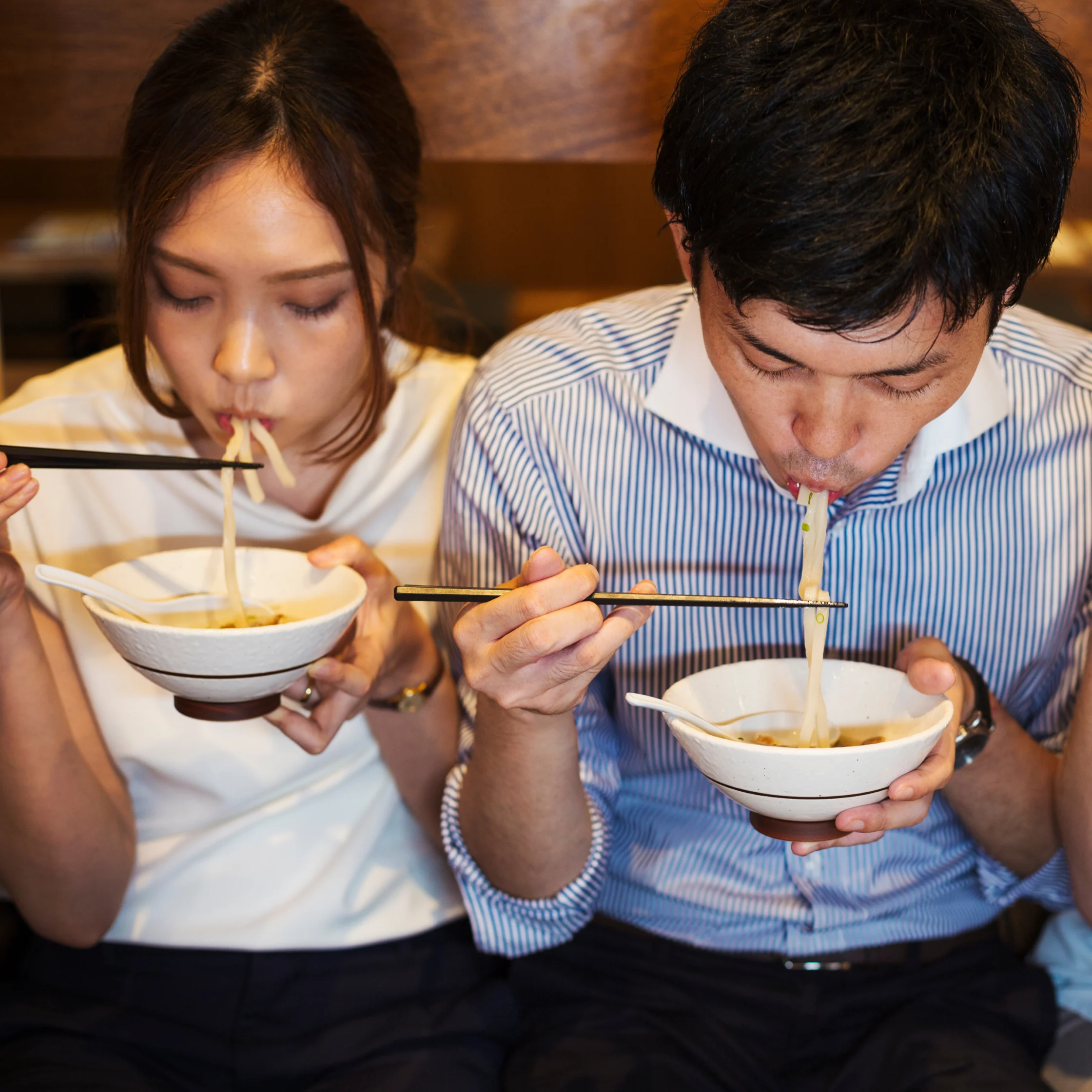 people slurping bowls of ramen in a savory broth
