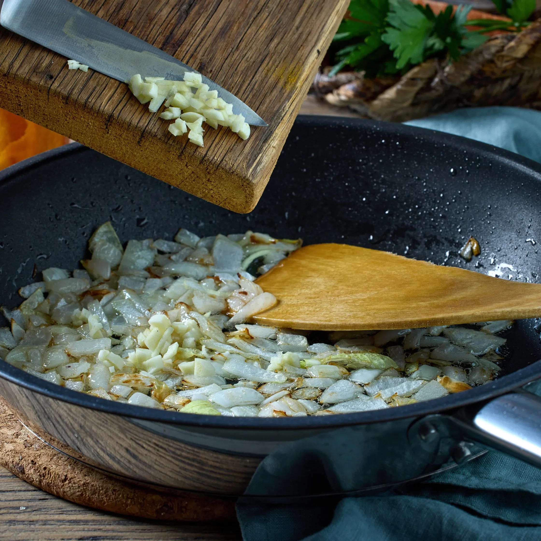 Chopped onions on a wooden cutting board with a knife nearby, ready for cooking.