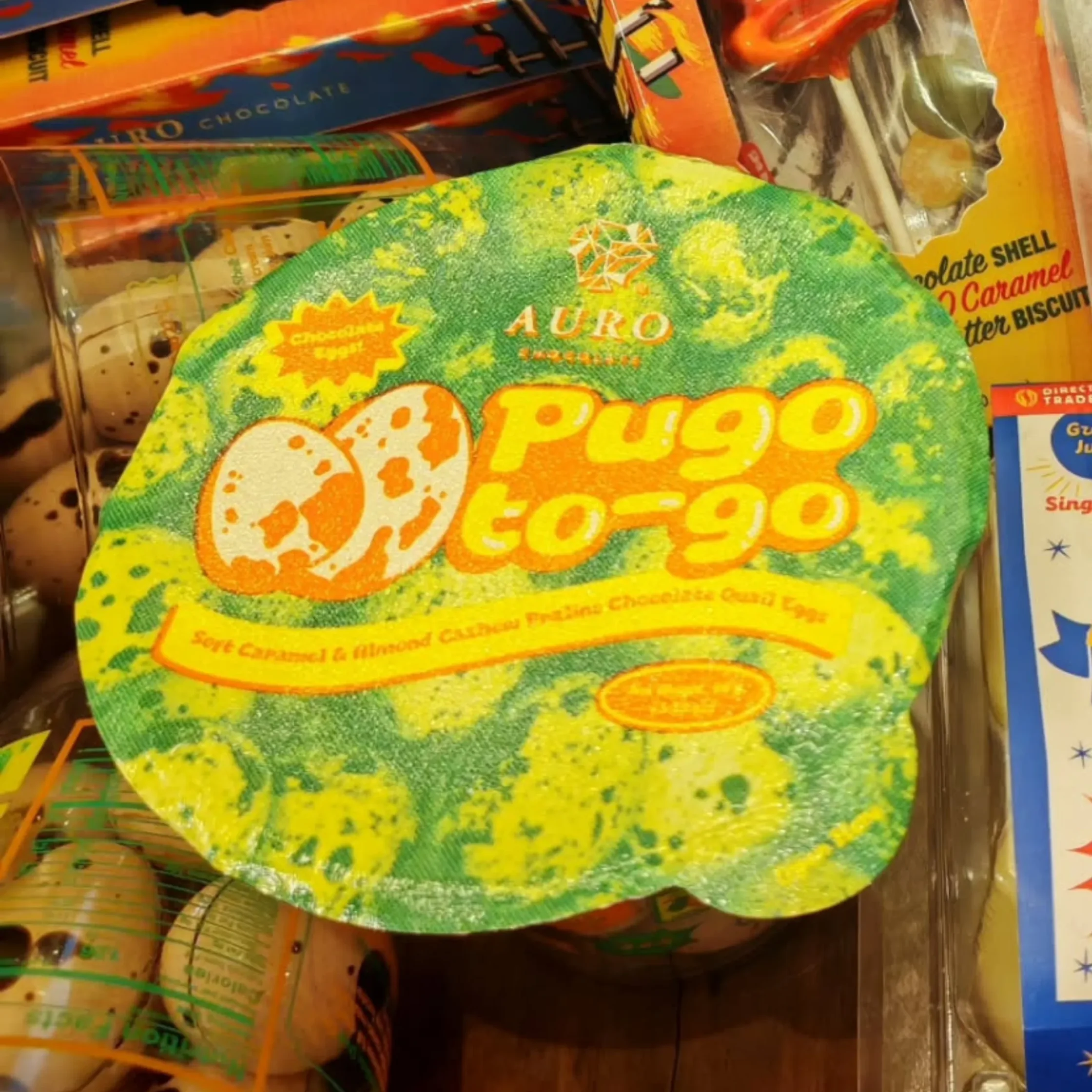 Close-up of colorful snack wrappers on a store shelf, with bright green and yellow swirls and orange text