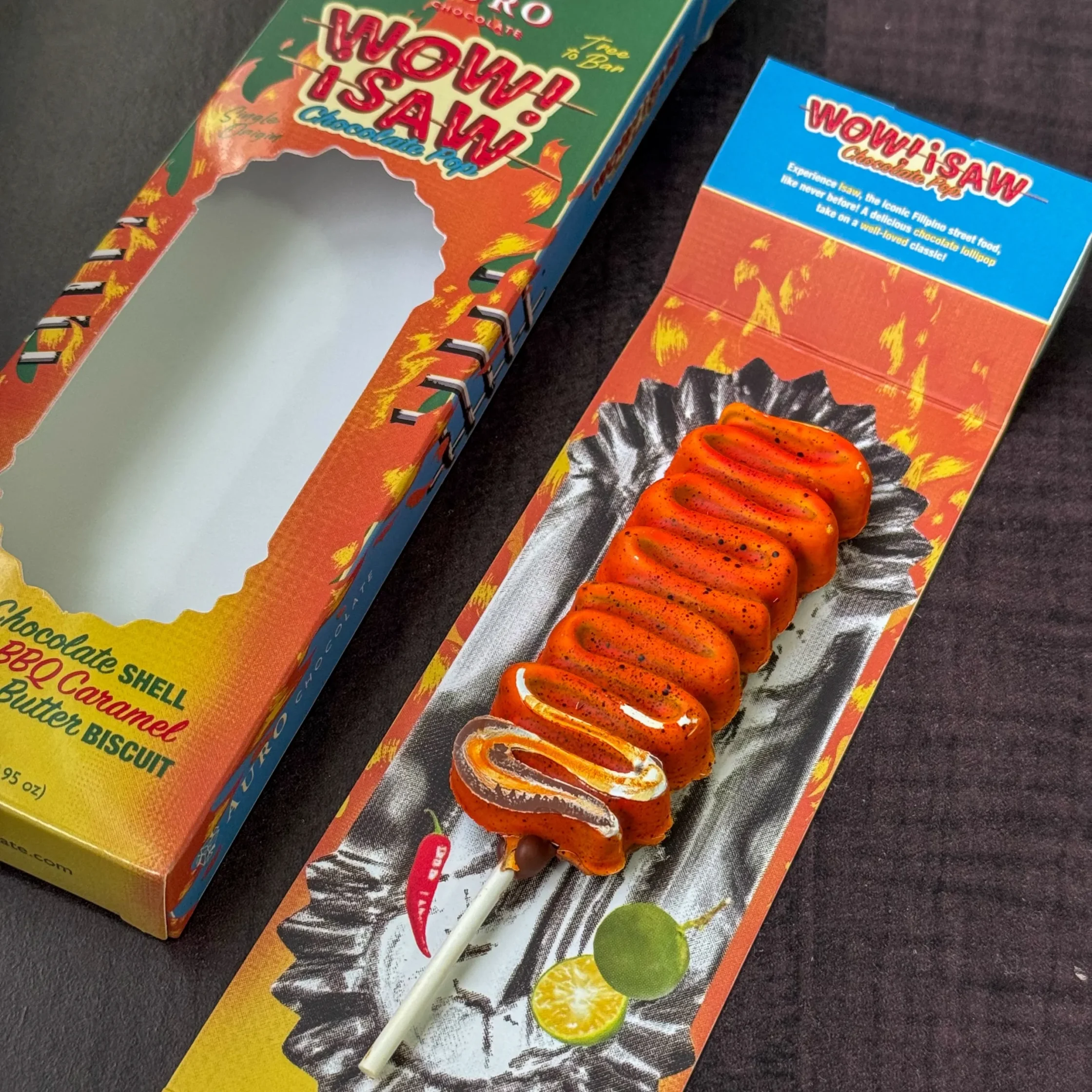 Boxed snacks with bright orange chocolate-dipped treats on a striped wrapper; visible text reads 'Wow! Isaw' and 'Chocolate' on green/orange packaging.
