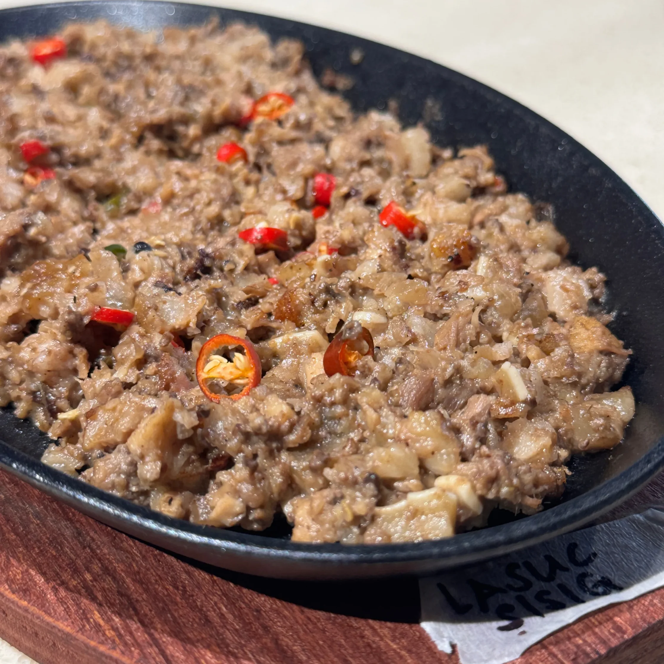 Close-up of cooked ground beef with small red chili pepper pieces in a black skillet