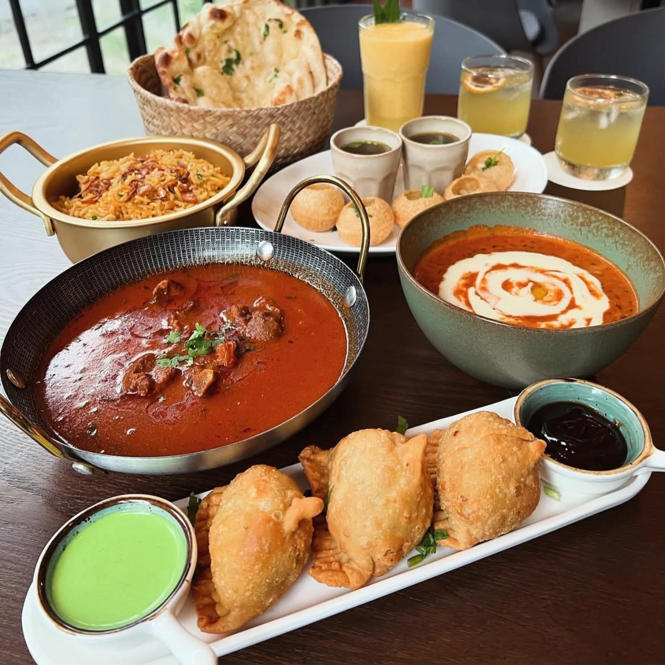 spread of indian food with samosas curries and naans at brick corner