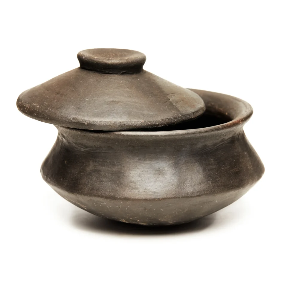 Close-up of a dark ceramic pot lid with a small knob, resting on a matching jar.