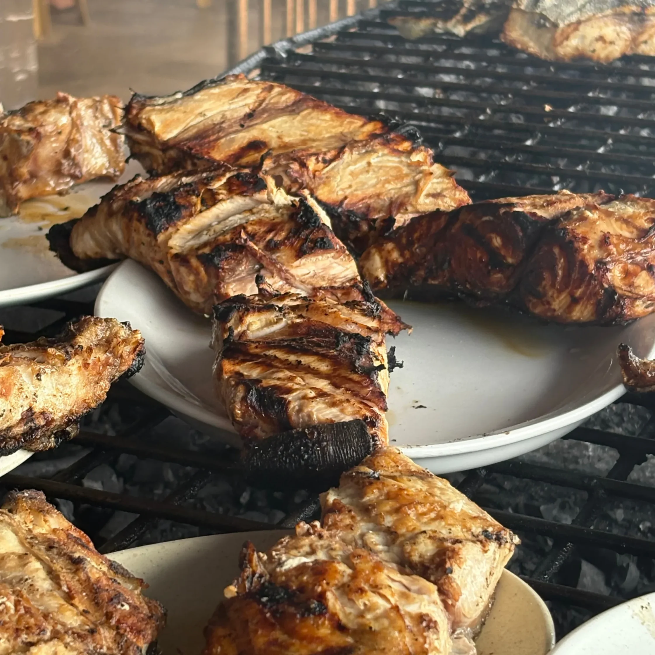 Barbecued chicken pieces with crispy, charred skin on a grill grate.