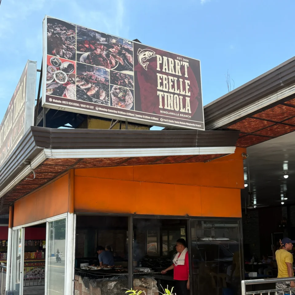 Restaurant sign with a collage of grilled meats and bold white lettering advertising a meat-focused eatery far above street level.