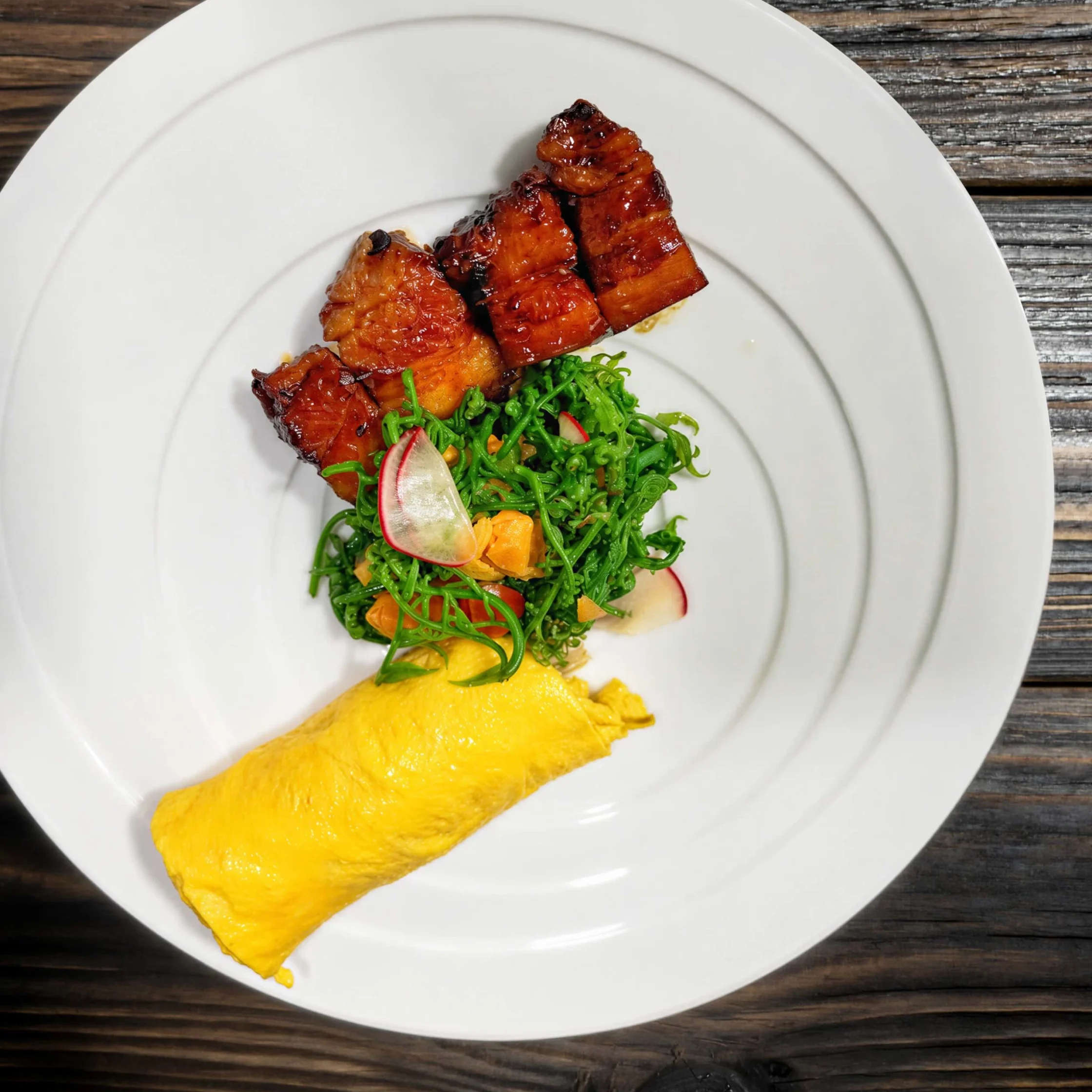 White plate featuring glazed barbecued pork slices arranged atop a green salad with radish slices on a wooden table surface