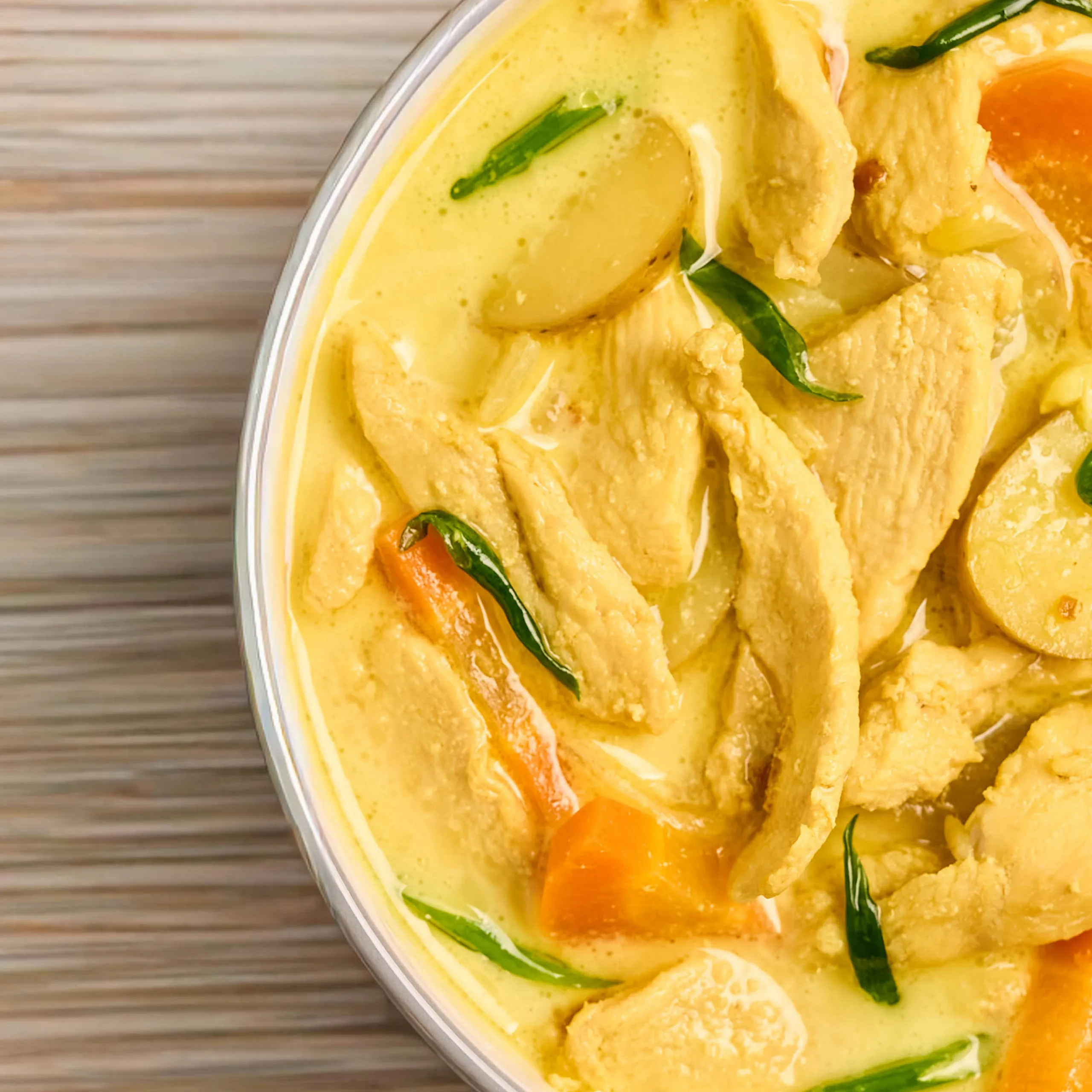 Creamy yellow chicken curry with green onions in a metal serving dish.
