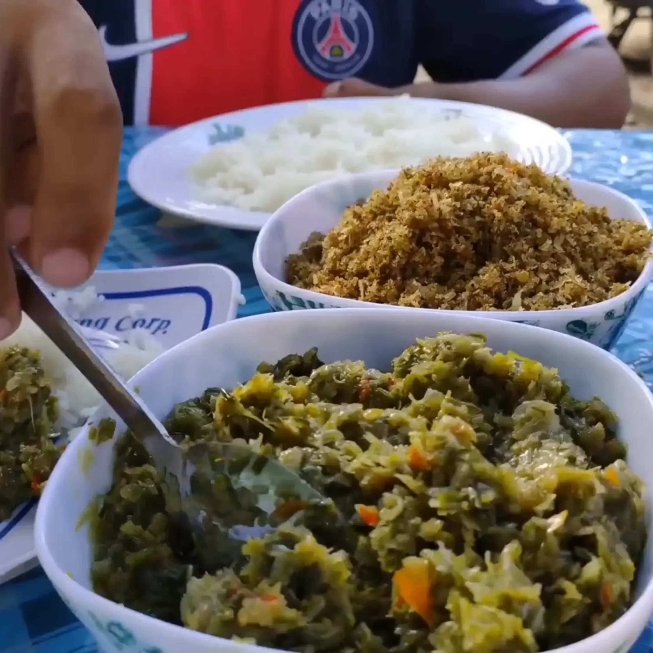Bowl of fried rice with chopped vegetables on a blue table, another bowl of white rice visible in the background.
