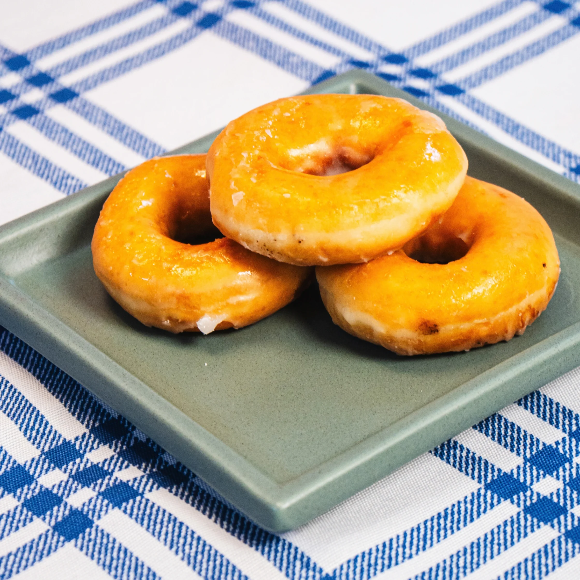 three pieces of donut stacked on a square green plate