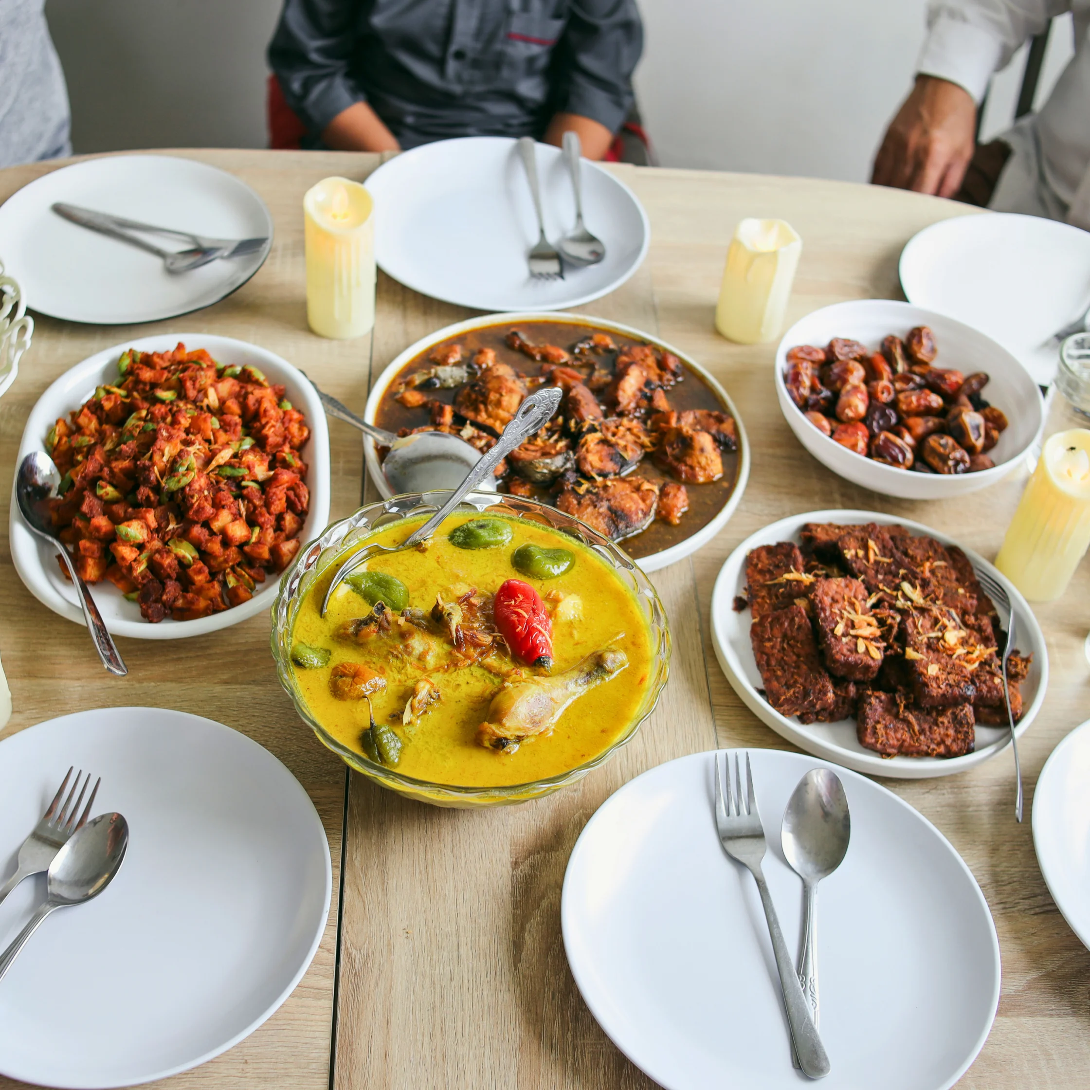 filipino food spread on a table with plates and people