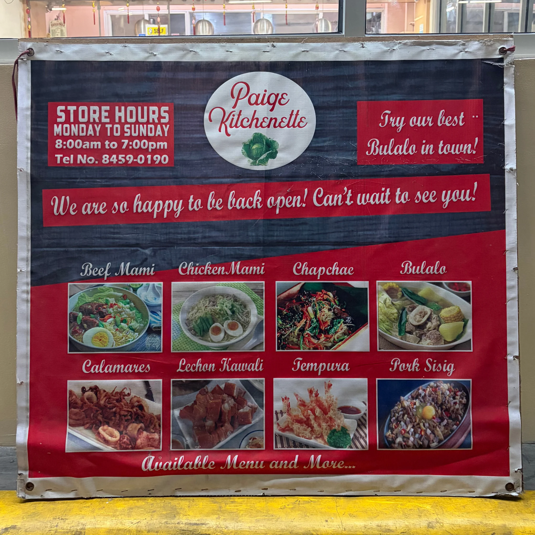 A red and black market banner for Paige’s Kitchenette lists store hours, celebrates reopening, and features photos of Filipino dishes like sisig and calamares.